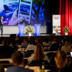 Das Bild zeigt einen Vortragenden vor Publikum auf der Bühne des NordseeTourismustages 2025 in Cuxhaven.