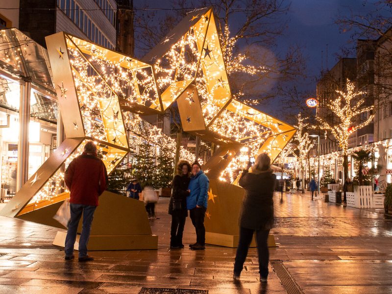 Das Bild zeigt einen großen, begehbaren und illuminiereten Weihnachtssterm in der Fußgängerzone von Bremerhaven. Menschen machen Fotos von sich und dem Stern.