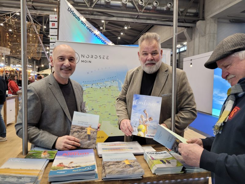 Das Bild zeigt einen Messestand mit den zwei Personen: Mario Schiefelbein (Tourismus-Agentur Nordsee GmbH) und Olaf Raffel (Nordseeheilbad Cuxhaven GmbH) werben auf der Ferien-Messe in Wien für die niedersächsische Nordsee.