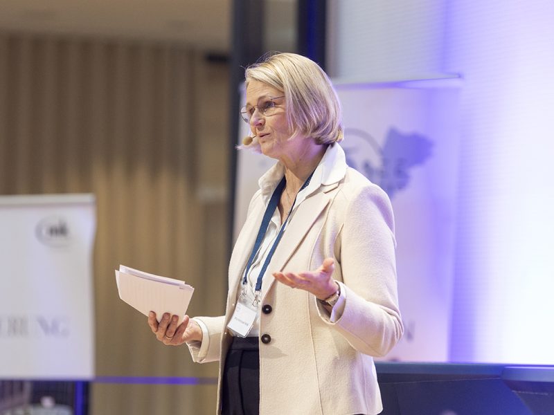 Anja Karliczek als Rednerin mit Handzettel und einem Mikrofon auf der Bühne beim NordseeTourismusTag 2026 in Leer