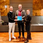 Das Bild zeigt, wie Danny Rudolf (HolidayCheck) den HolidayCheck Award 2026 an Kristian Kamp, Hoteldirektor des Strandhotels Duhnen, und Caroline Rennert, Marketing Managerin, überreicht..